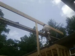Carpenter setting a ridge beam over a new addition frame — Ice Dam Removal by Roofing Brothers in Bejou