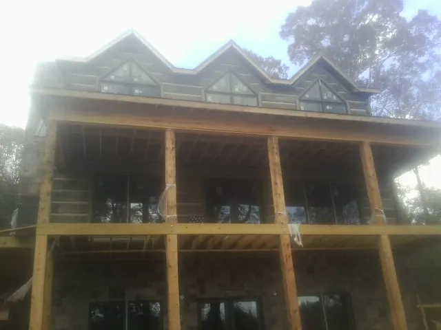 Dormers and porch framing on a large log home under construction — Roof Coating work by our crew in Bejou