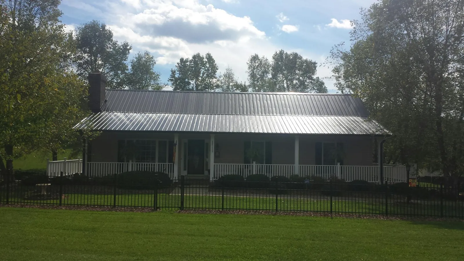 Gray metal roof on a brick ranch with a full width front porch — Gutter Guard Installation work by our crew in Bejou