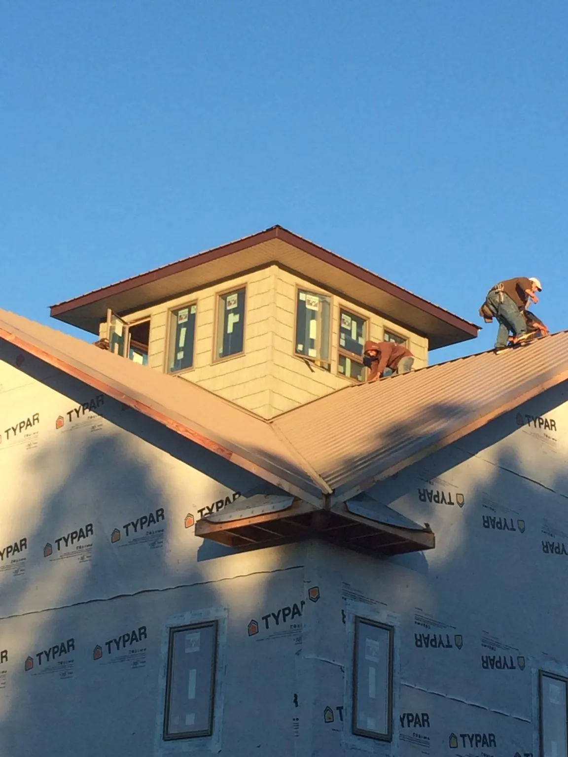 Roofers working around a rooftop cupola on a new metal roof at sunset — Roof Waterproofing in Bejou by Roofing Brothers